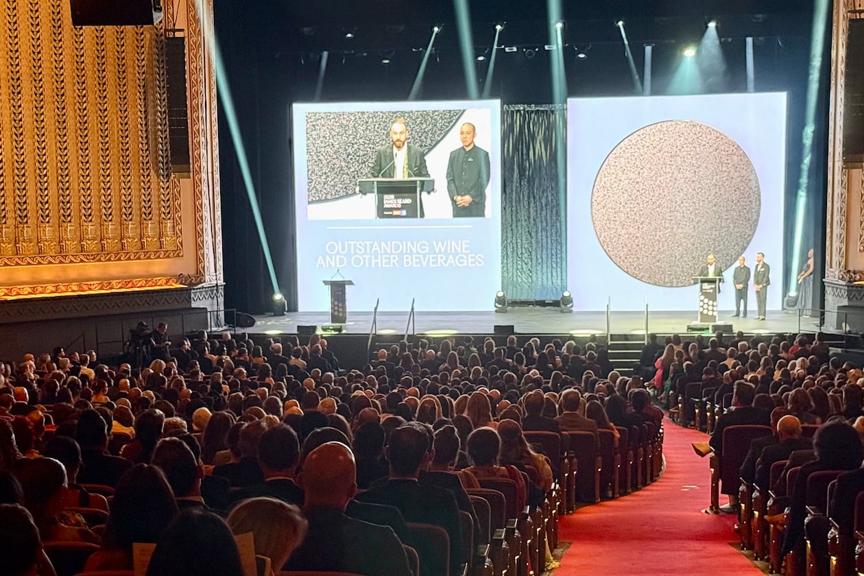 A packed theater with two presenters on stage.