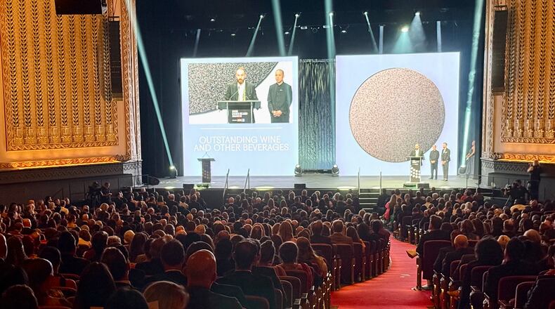 A packed theater with two presenters on stage.