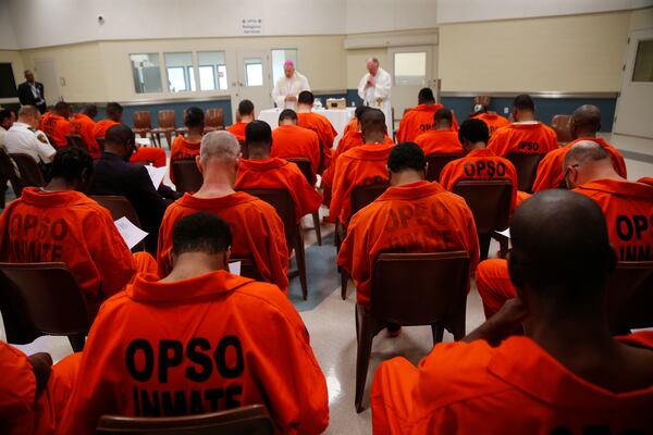 FILE - New Orleans Archbishop Gregory Aymond leads a Holy Thursday prayer service with Orleans Parish Prison Chaplain Father Terry Hayden, right, at the Orleans Justice Center in New Orleans on April 13, 2017. (AP Photo/Gerald Herbert, File)