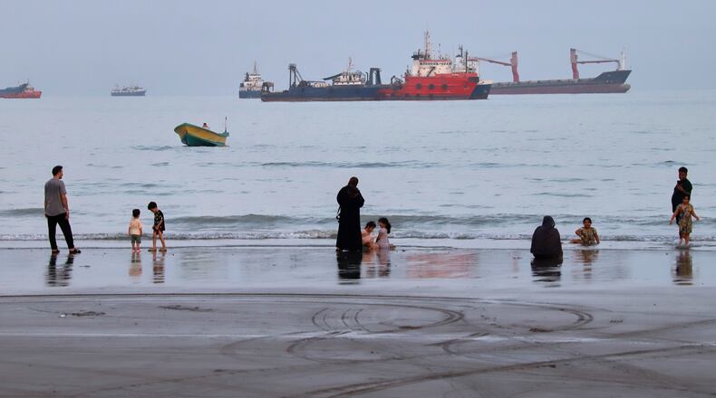 People spend time at a beach as commercial vessels are anchored in the Strait of Hormuz off Bandar Abbas, Iran, Wednesday, Aug. 5, 2026. (Amirhosein Khorgooi/ISNA via AP)