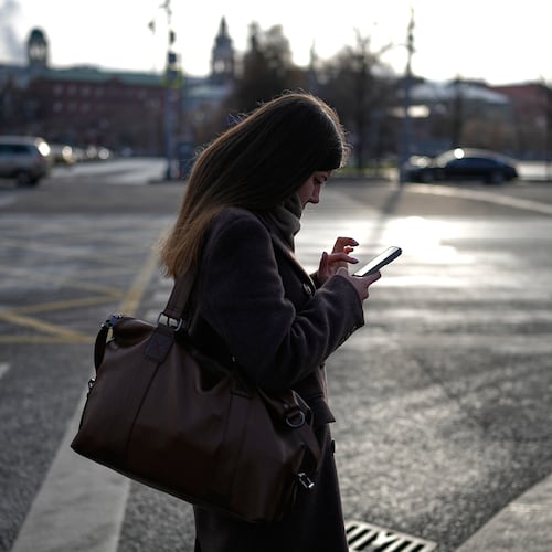 A woman looks at her smartphone in central Moscow, Russia, Thursday, Nov. 20, 2025. (AP Photo/Alexander Zemlianichenko)