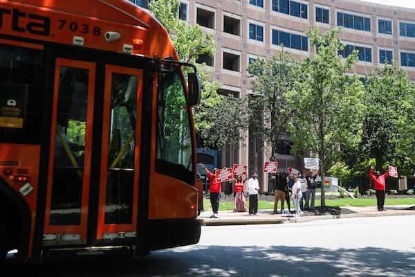 Protesters hold signs as a MARTA bus drives by outside of the MARTA Headquarters in Atlanta on Thursday, June 11, 2026. (Abbey Cutrer/AJC)