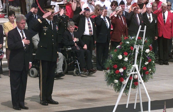 FILE - President Clinton stands with his hand over his heart during the playing of "Taps" at the Tomb of the Unknowns during Memorial Day ceremonies at Arlington National Cemetery Monday, May 25, 1998 in Arlington, Va. Standing next to the President is Major Gen. Robert Foley, the commanding general of the Military District of Washington. (AP Photo/Susan Walsh, File)