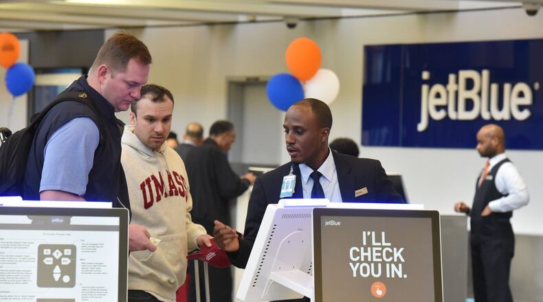 Kevon Shepherd (right) with JetBlue, assists customers at the JetBlue Airlines ticketing at Hartsfield-Jackson Atlanta International Airport on Friday, April 7, 2017. HYOSUB SHIN / HSHIN@AJC.COM