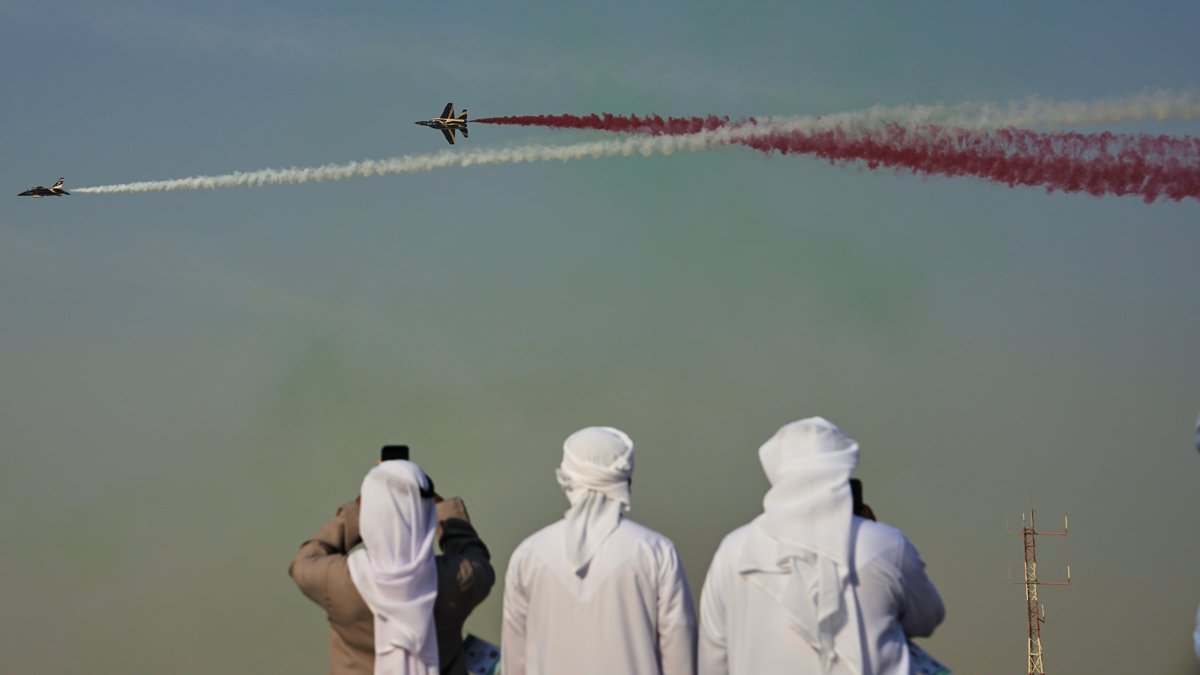 Emirati men take photos of Fursan Al Emarat, the aerobatics demonstration team of the United Arab Emirates Air Force during the Dubai Air Show in Dubai, United Arab Emirates, Tuesday, Nov. 18, 2025. (AP Photo/Fatima Shbair)