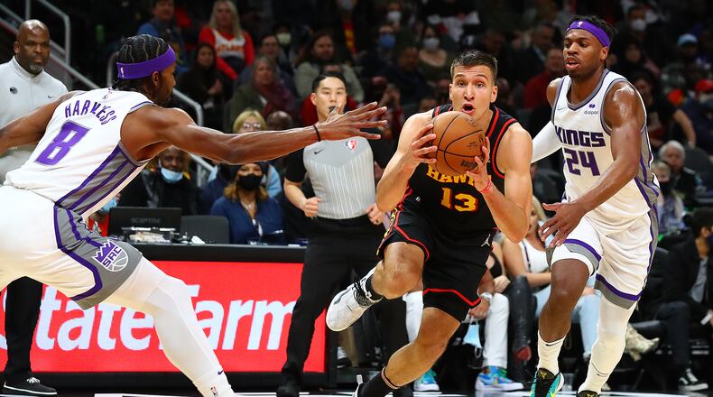 Hawks guard Bogdan Bogdanovic drives with the steal against Sacramento Kings Maurice Harkless (left) and Buddy Hield in a NBA basketball game on Wednesday, Jan. 26, 2022, in Atlanta. “Curtis Compton / Curtis.Compton@ajc.com”`