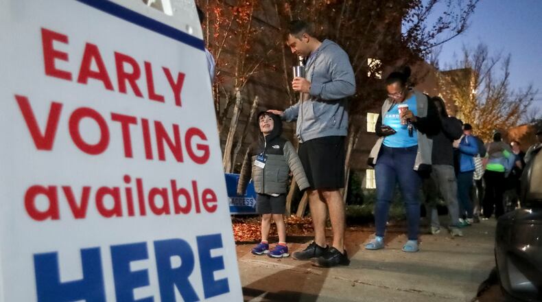 Josh Weeks waits in line with son, Noah-4 as early voters hit the polls Friday, Nov. 4, 2022 at the Joan P. Garner Library in Atlanta.  (John Spink / John.Spink@ajc.com)