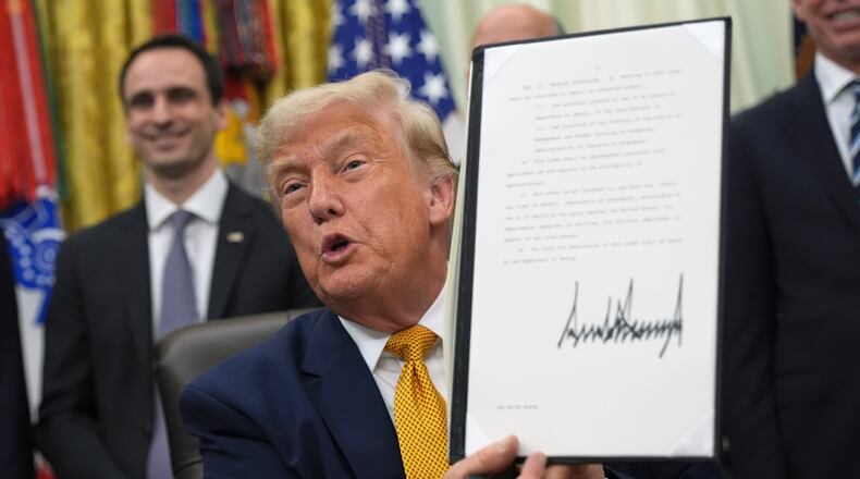 President Donald Trump holds up a signed executive order about quantum computing, in the Oval Office of the White House, Monday, June 22, 2026, in Washington. (AP Photo/Jacquelyn Martin)