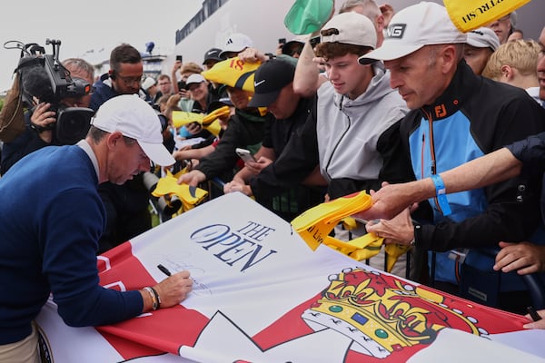 Rory McIlroy of Northern Ireland signs a replica Northern Ireland flag on the 18th green following a practice round for the 2025 British Open golf championship at the Royal Portrush Golf Club, Northern Ireland, Monday, July 14, 2025. (AP Photo/Peter Morrison)