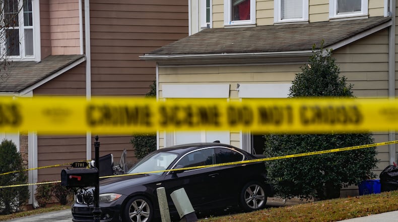 Crime scene tape encircles a house in a South Fulton neighborhood after two men were shot to death Wednesday.