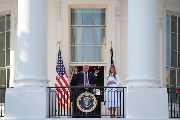 President Donald Trump speaks from the Blue Rom Balcony as first lady Melania Trump listens before he signs his signature bill of tax breaks and spending cuts at the White House, Friday, July 4, 2025, in Washington. (AP Photo/Evan Vucci)
