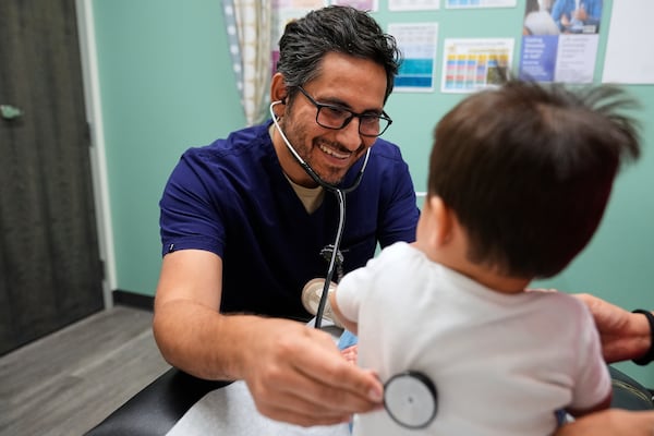 Pediatrician Irving Phillips, left, examines a 16-month-old boy at a CommuniCARE+OLE clinic Thursday, June 26, 2025, in Davis, Calif. (AP Photo/Godofredo A. Vásquez)