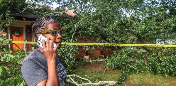 Leisa Stafford talks on the phone outside her Mesa Drive home that was crushed by a tree Thursday morning. Stafford escaped out of a bathroom window.