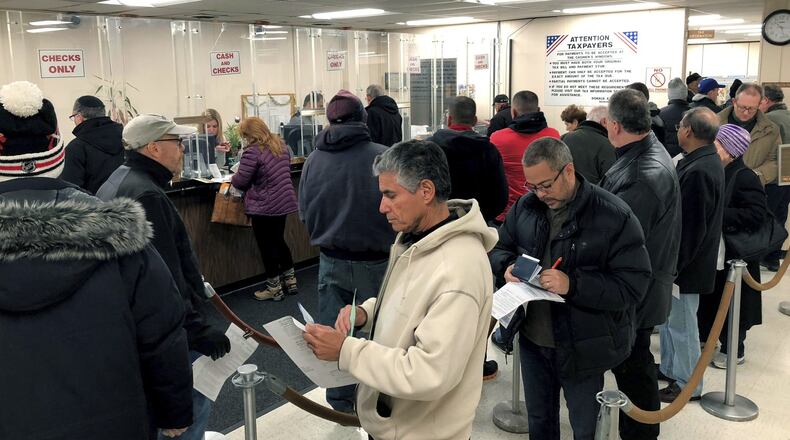 People line up to pay their real estate taxes before the end of the year, hoping for one last chance to take advantage of a major tax deduction before it is wiped out in the new year. The tax overhaul signed last week by President Donald Trump puts a new $10,000 limit on the amount of state and local taxes people can deduct from their income when calculating their federal tax liability. (Howard Schnapp/Newsday via AP)