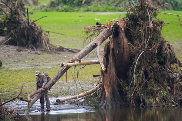 A Texas Department of Public Safety official inspects tree debris at Camp Mystic along the Guadalupe River after a flash flood swept through the area Sunday, July 6, 2025, in Hunt, Texas. (AP Photo/Julio Cortez)