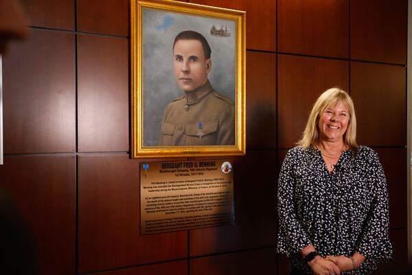 Sue Williams, granddaughter of Sgt. Fred G. Benning, stands in front of a painting of her grandfather Wednesday at Fort Benning. (Natrice Miller/AJC)