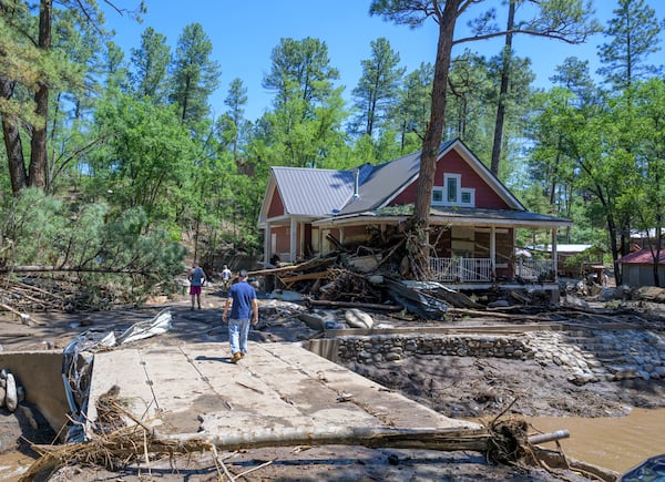 Residents of the town of Ruidoso, N.M., walk back to their neighborhood to find what's left of their homes a day after major flooding washed away properties leaving streets clogged with mud and debris, along the Rio Ruidoso, Wednesday, July 9, 2025, in Ruidoso, N.M. (AP Photo/Roberto E. Rosales)