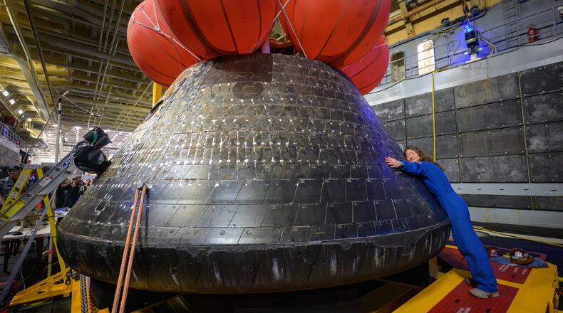 In this photo provided by NASA, Artemis II mission specialist and NASA astronaut Christina Koch hugs the Orion spacecraft aboard the USS John P. Murtha, Saturday, April 11, 2026, off the coast of California. (Bill Ingalls/NASA via AP)