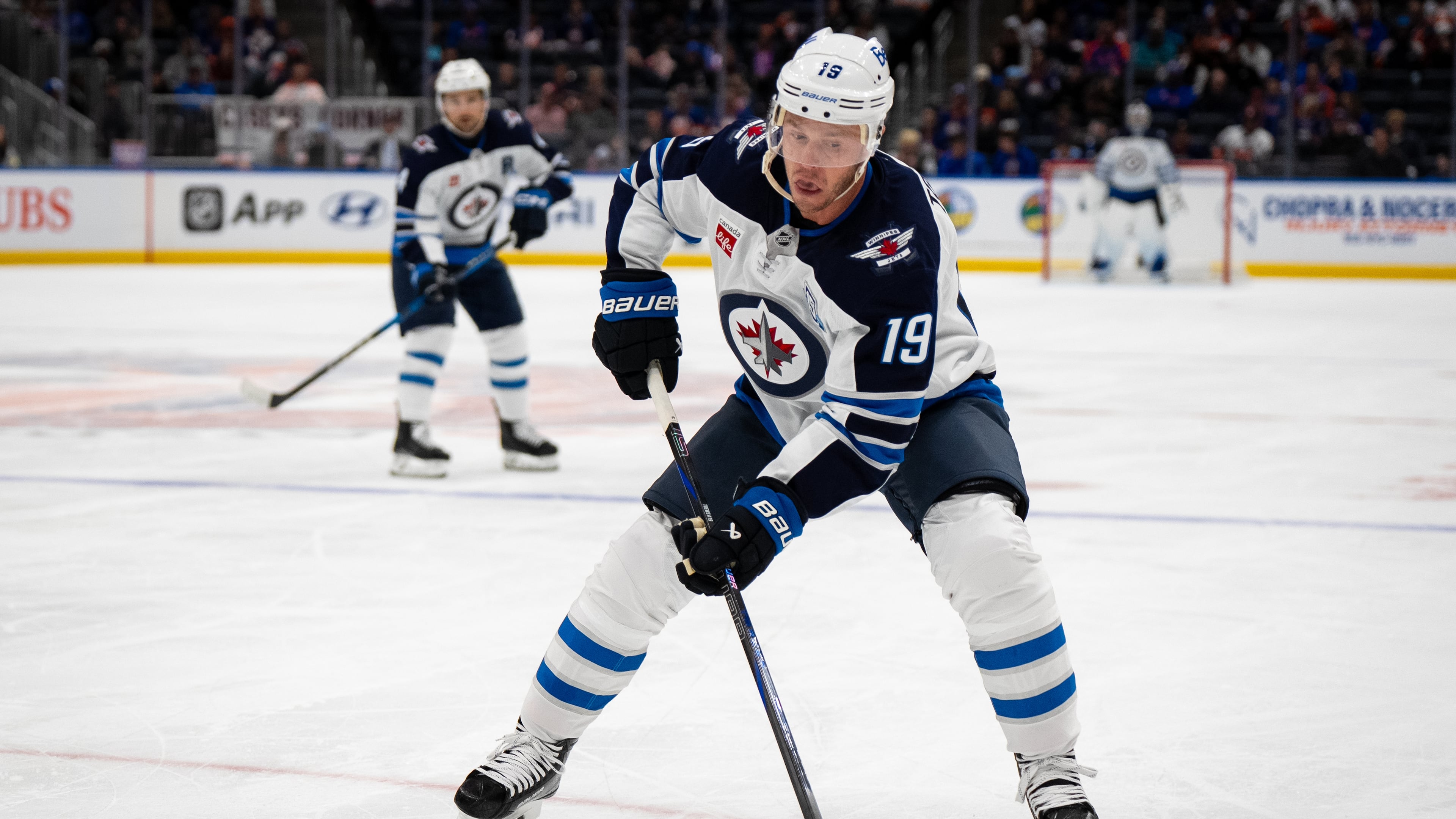 Winnipeg Jets center Jonathan Toews (19) controls the puck during the second period of an NHL hockey game against the New York Islanders, Monday, Oct. 13, 2025, in Elmont, N.Y. (AP Photo/Angelina Katsanis)