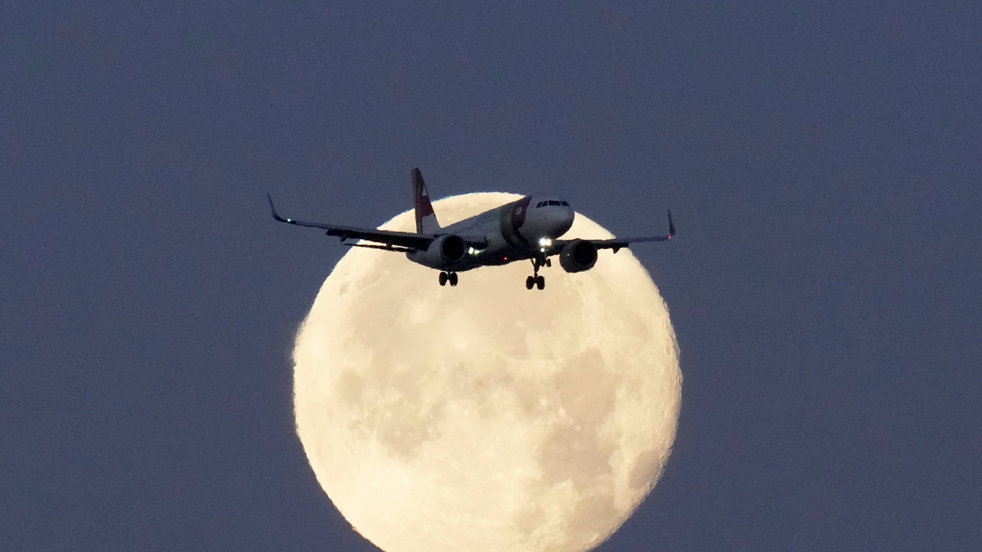 FILE - A TAP Air Portugal Airbus A320 is silhouetted against the setting moon while approaching for landing in Lisbon, Portugal, June 23, 2024. (AP Photo/Armando Franca, File)
