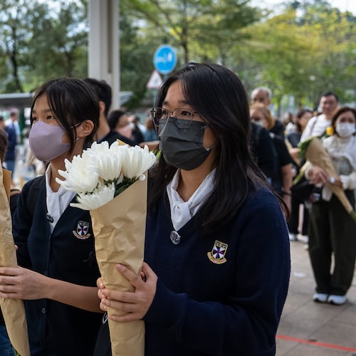People offer flowers for the victims near the site of a deadly Wednesday fire at Wang Fuk Court, a residential estate in the Tai Po district of Hong Kong's New Territories on Monday, Dec. 1, 2025. (AP Photo/Chan Long Hei)