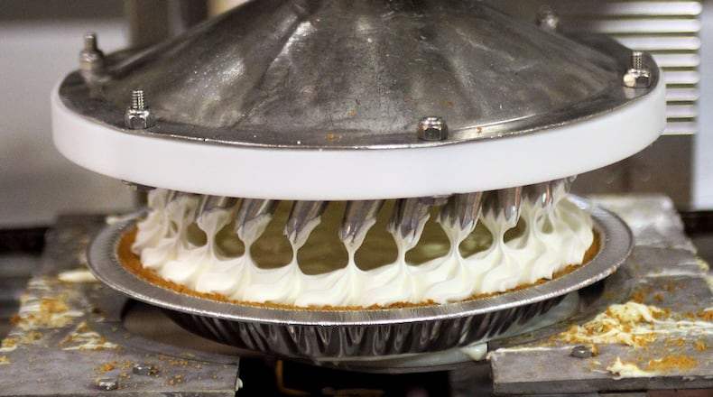 Specially designed nozzles makes a creamy ring around a key lime pie on an assembly line at the Edwards pie plant in central Atlanta. The facility that sends the smell of baking pies throughout Inman Park and Reynoldstown. The plant produces 140,000 pies a day and about 42 million a year. It has been at it's current location since 1970. / AJC file photo