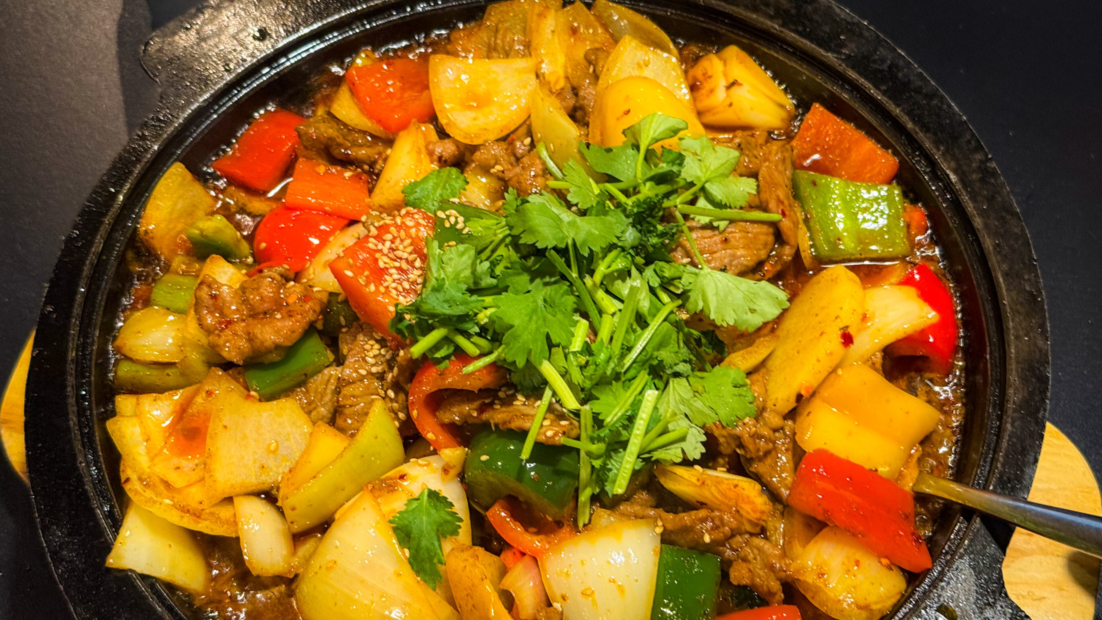 Stone pot beef at Chilispot in Duluth is served in an enormous, superheated vessel that keeps the dish sizzling long after it arrives at the table. (Henri Hollis/AJC)
