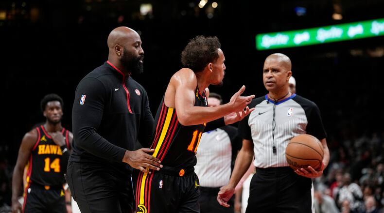 Atlanta Hawks guard Trae Young (11) is restrained after his was ejected during the second half of an NBA basketball game, Monday, Dec. 11, 2023, in Atlanta. (AP Photo/John Bazemore)