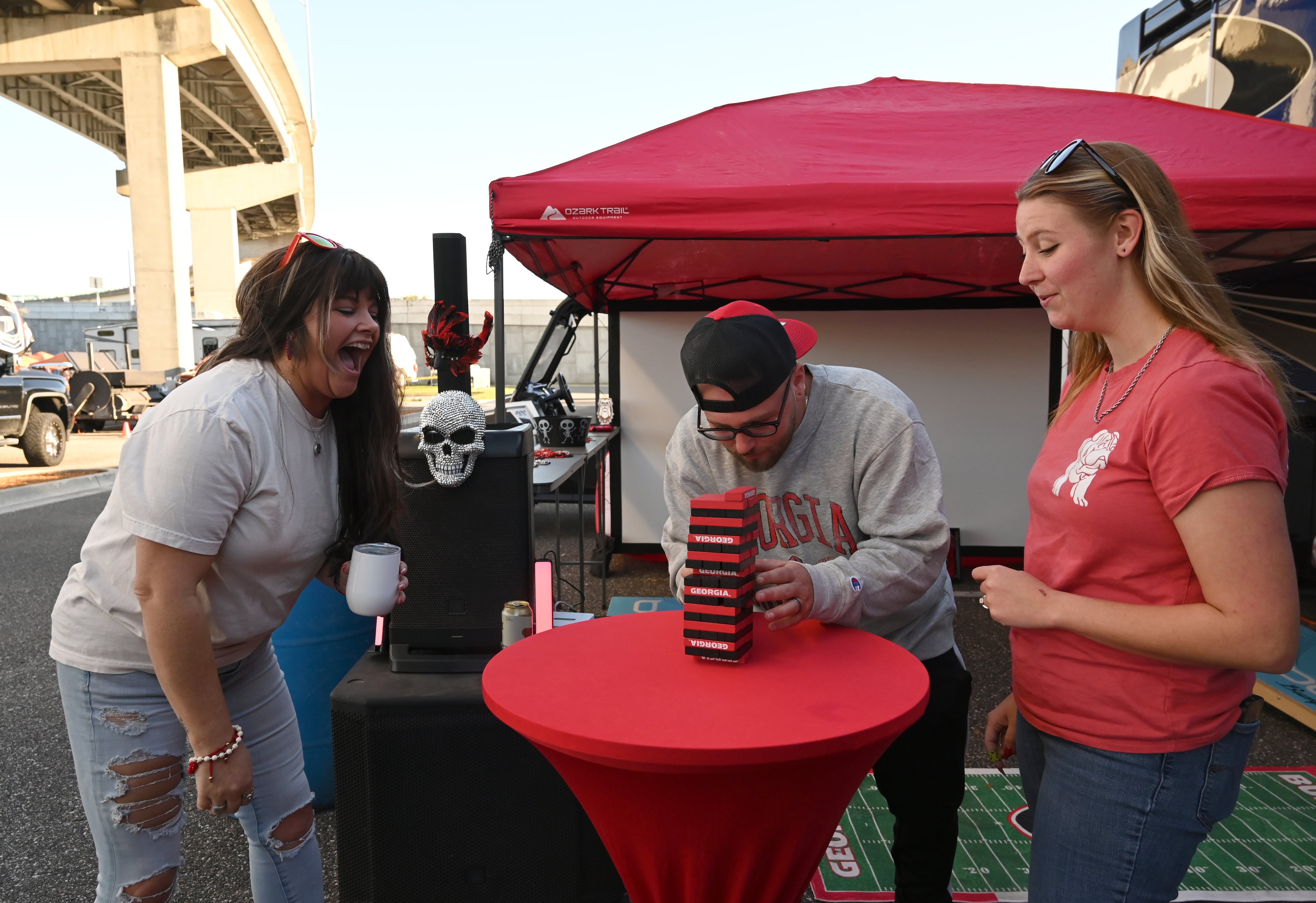 Georgia fans (left) Tonia Weeks plays Jenga with her daughter Amanda Kennedy (right) and husband Devin Kennedy during tailgating ahead of the NCAA football game Saturday between Georgia and Florida in RV City outside EverBank Stadium, Friday, October 31, 2025, Jacksonville, Fla. (Hyosub Shin / AJC)