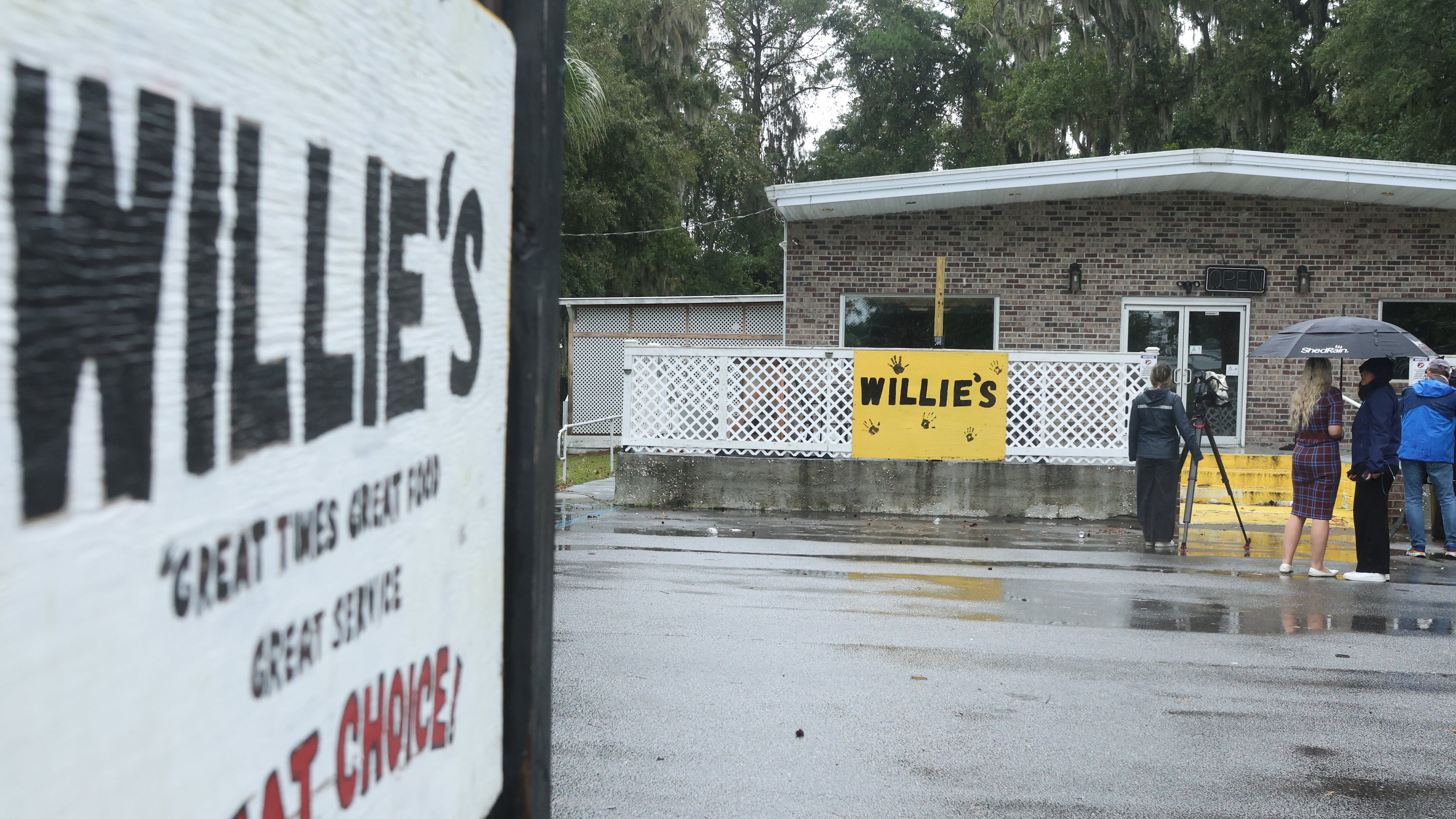 People stand outside of Willie's Bar and Grill in St Helena Island, S.C. after a shooting occurred early Sunday, Oct. 12, 2025. (AP Photo/Lewis M. Levine)