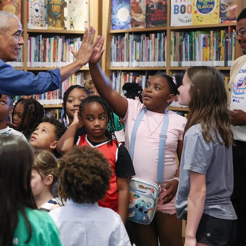 Former President Barack Obama gives a high-five during a book reading with children on opening day of the Barack Obama Presidential Center in John Lewis Plaza, Friday, June 19, 2026, in Chicago. (Win McNamee/Pool Photo via AP)