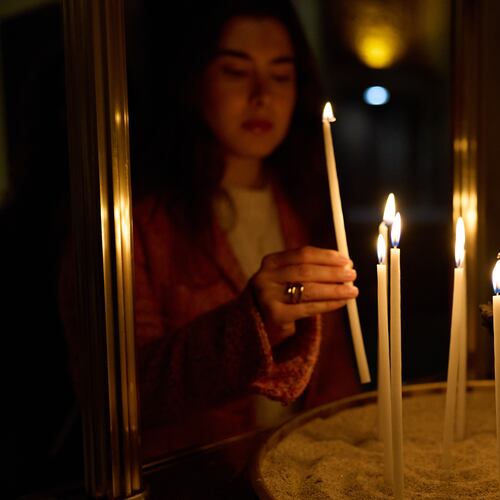 A person lights a candle during service at St. Sophia Greek Orthodox Cathedral Tuesday, Nov. 18, 2025, in Los Angeles. (AP Photo/Allison Dinner)