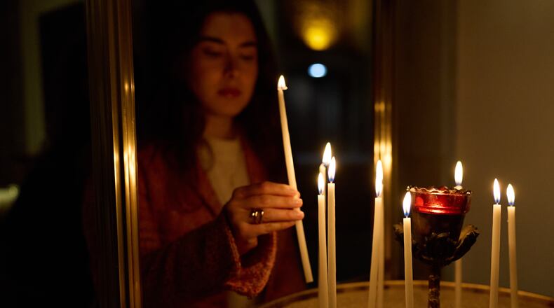 A person lights a candle during service at St. Sophia Greek Orthodox Cathedral Tuesday, Nov. 18, 2025, in Los Angeles. (AP Photo/Allison Dinner)