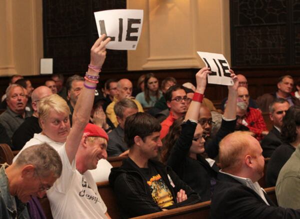 A TOUGH ROOM--Some audience members hold up signs to disagree with an answer by Mayor Kasim Reed and APD Chief George Turner at the Atlanta Police Department LGBT Advisory Board Community Town Hall Meeting to discuss the Atlanta Eagle raid and the city's response to the aftermath at St. Mark United Methodist Church in Atlanta on Tuesday, Nov. 1, 2011.