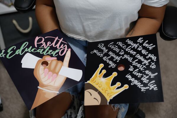 Bria Bowen holds up digital designs for graduation caps that she created for various clients on Wednesday, April 19, 2023. (Natrice Miller/natrice.miller@ajc.com)