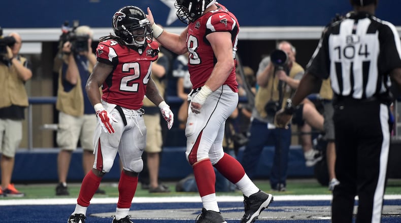 Atlanta Falcons' Devonta Freeman (24) and Mike Person, right, celebrate a touchdown score by Freeman in the second half of an NFL football game against the Dallas Cowboys on Sunday, Sept. 27, 2015, in Arlington, Texas. (AP Photo/Michael Ainsworth)