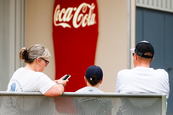 A family sits outside of the World of Coca-Cola in Atlanta on Saturday, July 19, 2025. President Trump recently declared that Coca-Cola will use cane sugar in its sodas rather than high-fructose corn syrup. (Abbey Cutrer / AJC)