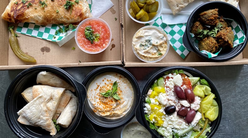 This takeout spread from Vertigo Cafe includes (clockwise from upper left): ziva with accompaniments; falafel; Greek salad; hummus and pita. Wendell Brock for The Atlanta Journal-Constitution