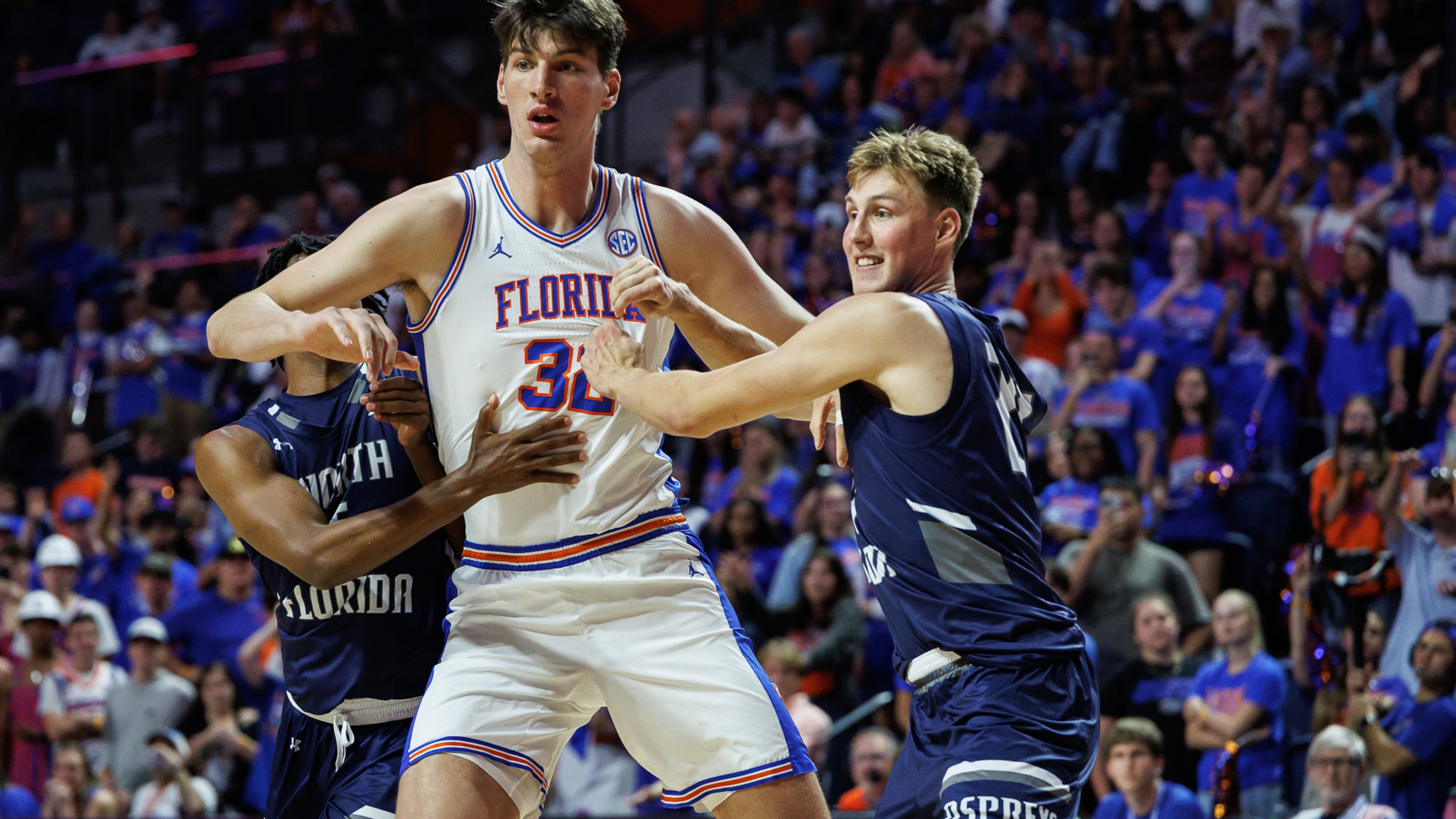 CORRECTS TO SECOND HALF NOT FIRST HALF - North Florida guard Dante Oliver, left and North Florida forward Nestor Dyachok, right, guard against Florida center Olivier Rioux, center, during the second half of an NCAA college basketball game Thursday, Nov. 6, 2025, in Gainesville, Fla. (AP Photo/Chris Watkins)
