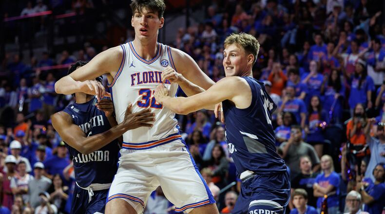 CORRECTS TO SECOND HALF NOT FIRST HALF - North Florida guard Dante Oliver, left and North Florida forward Nestor Dyachok, right, guard against Florida center Olivier Rioux, center, during the second half of an NCAA college basketball game Thursday, Nov. 6, 2025, in Gainesville, Fla. (AP Photo/Chris Watkins)
