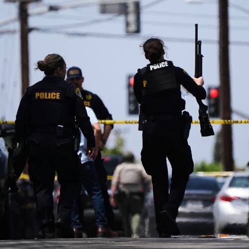 People carry weapons at the scene of a shooting outside the Islamic Center of San Diego Monday, May 18, 2026, in San Diego. (AP Photo/Gregory Bull)