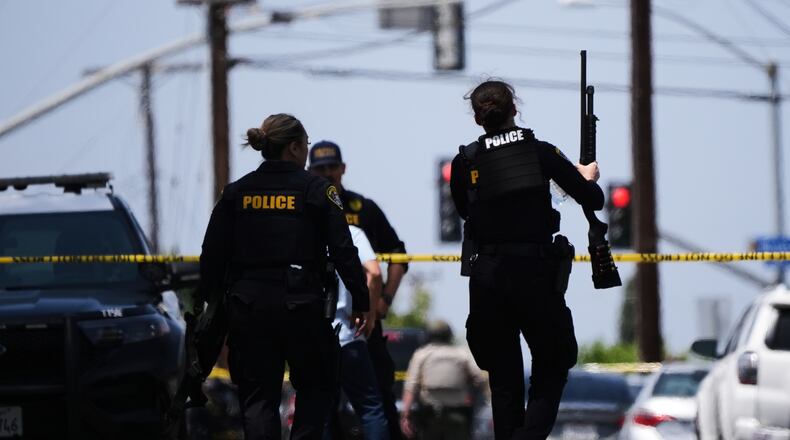 People carry weapons at the scene of a shooting outside the Islamic Center of San Diego Monday, May 18, 2026, in San Diego. (AP Photo/Gregory Bull)