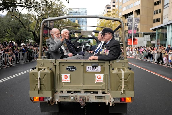 Veterans ride in the back of an army truck past thousands of people lining the street to pay tribute to their war dead during the Anzac Day parade in Sydney, Australia, Friday, April 25, 2025. (AP Photo/Rick Rycroft)