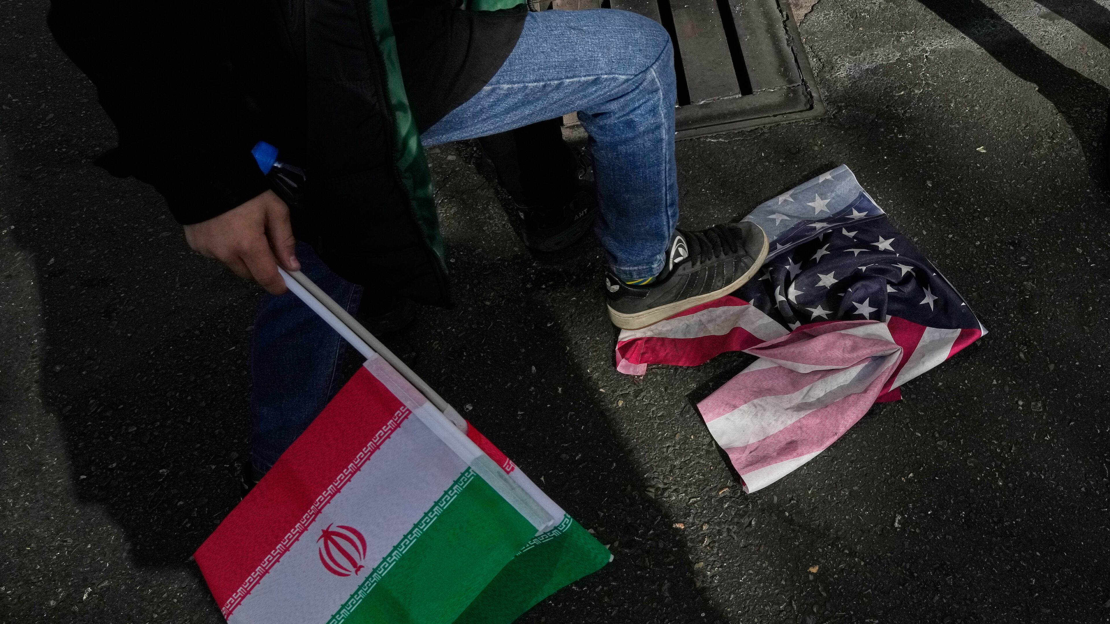 A school boy stomps a U.S. flag as he holds an Iranian flag during an annual rally in front of the former U.S. Embassy in Tehran, celebrating the anniversary of the 1979 takeover of the embassy, Iran, Tuesday, Nov. 4, 2025. (AP Photo/Vahid Salemi)