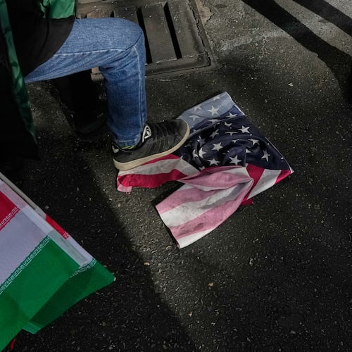 A school boy stomps a U.S. flag as he holds an Iranian flag during an annual rally in front of the former U.S. Embassy in Tehran, celebrating the anniversary of the 1979 takeover of the embassy, Iran, Tuesday, Nov. 4, 2025. (AP Photo/Vahid Salemi)