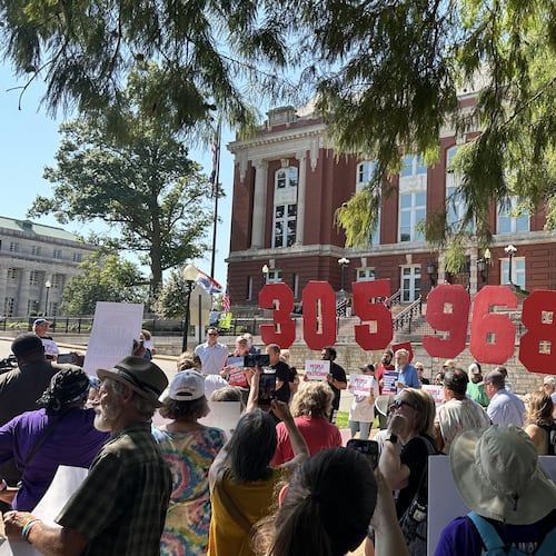 In this photo taken with a smartphone, people opposing a congressional redistricting plan rally outside the Missouri Supreme Court in Jefferson City, Mo., Wednesday, Sept. 2, 2026, while displaying the number of petition signatures submitted seeking a statewide vote on the measure. (AP Photo/David A. Lieb)