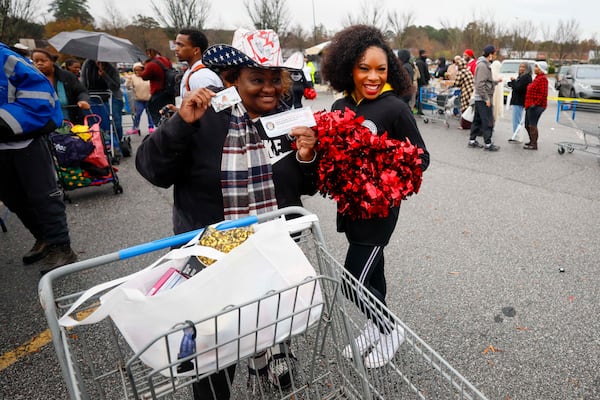 Pamela Brown from Atlanta poses with her Skyhawks ticket voucher and gift card alongside a Skyhawks cheerleader at the “Greens and Things" Thanksgiving giveaway on Tuesday, Nov. 24, 2025. (Miguel Martinez/AJC)