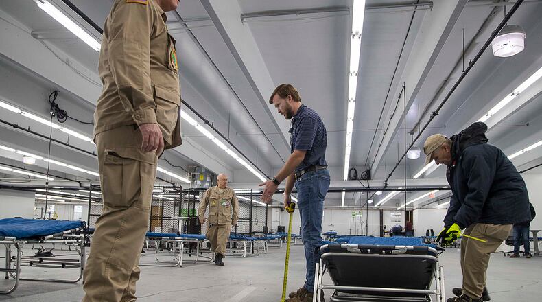 Lynn Jones (center), assistant project manager at Brasfield and Gorrie LLC, gives members of the U.S. Department of Health and Human Services Disaster Medical Assistance Team instructions on where beds can be situated inside of a newly constructed pop-up hospital located in the parking garage at Floyd Medical Center in Rome. The hospital is expanding capacity to prepare for a surge of coronavirus patients. (ALYSSA POINTER / ALYSSA.POINTER@AJC.COM)