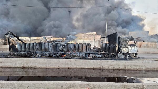 Smoke rises in background next to the gutted remains of a truck, Sunday, April 27, 2025, after a massive explosion and fire rocked a port near the southern port city of Bandar Abbas, Iran on Saturday. (AP Photo/Meysam Mirzadeh/Tasnim News)