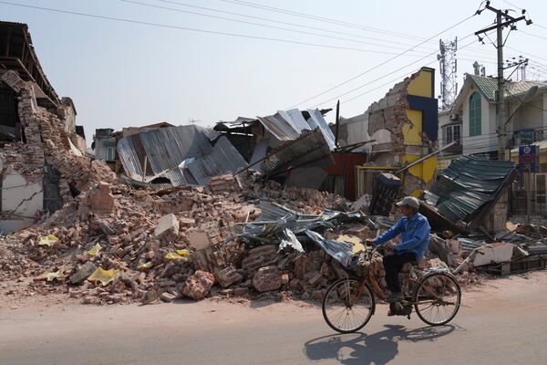 A local man rides a bicycle past a damaged building in the aftermath of an earthquake, in Naypyitaw, Myanmar, Sunday, March 30, 2025. (AP Photo/Aung Shine Oo)
